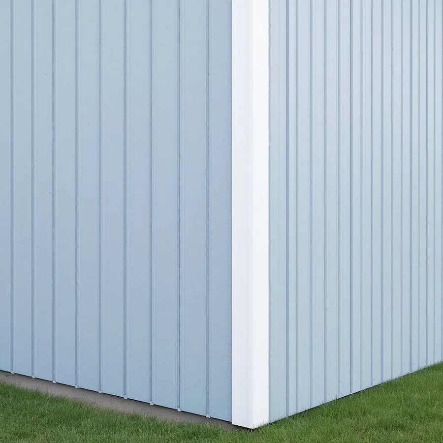 Outside corner of a house in pale blue gray board and batten siding with one white vertical corner board from the grass to the top of the picture