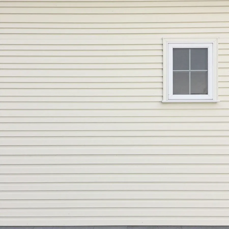 Cream lap siding in even horizontal courses with one small white trimmed window