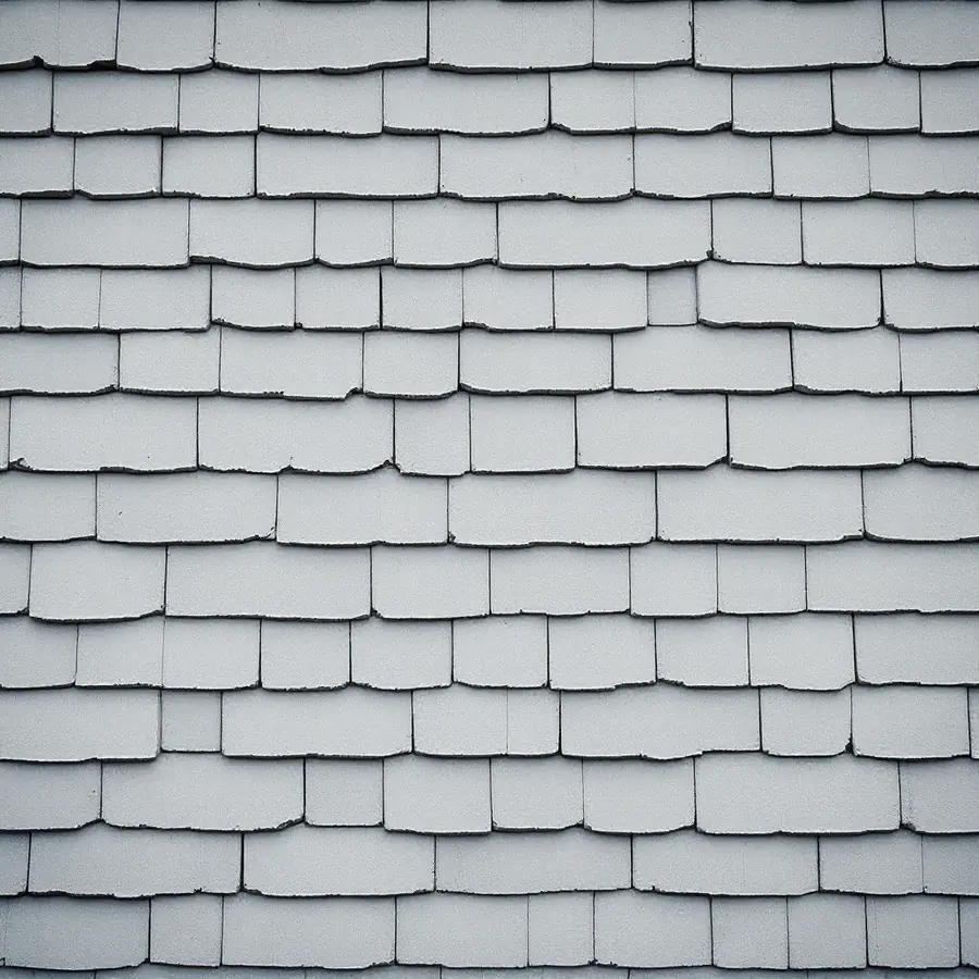 Wall of flat gray rectangular cement shingles with wavy lower edges laid in overlapping rows