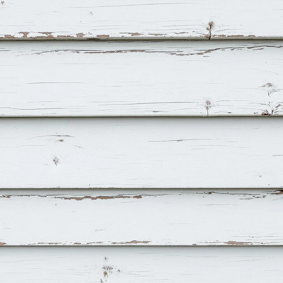 Old white painted wooden siding boards with cracked paint and thin open lines along the joints